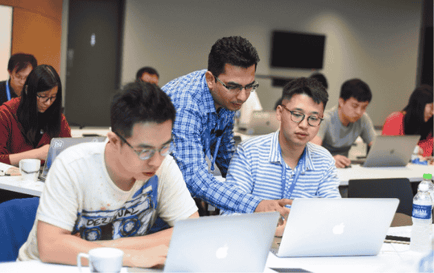Instructor guiding participants during a hands-on technical training session in a classroom setting